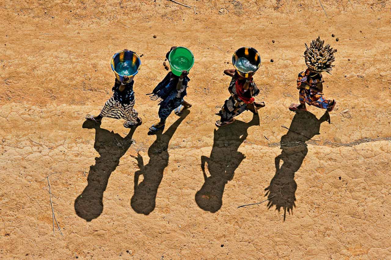 © Yann Arthus-Bertrand - Young girls carrying buckets in the Dogon region, near Bandiagara, Mali (14°20' N - 3°37' W).