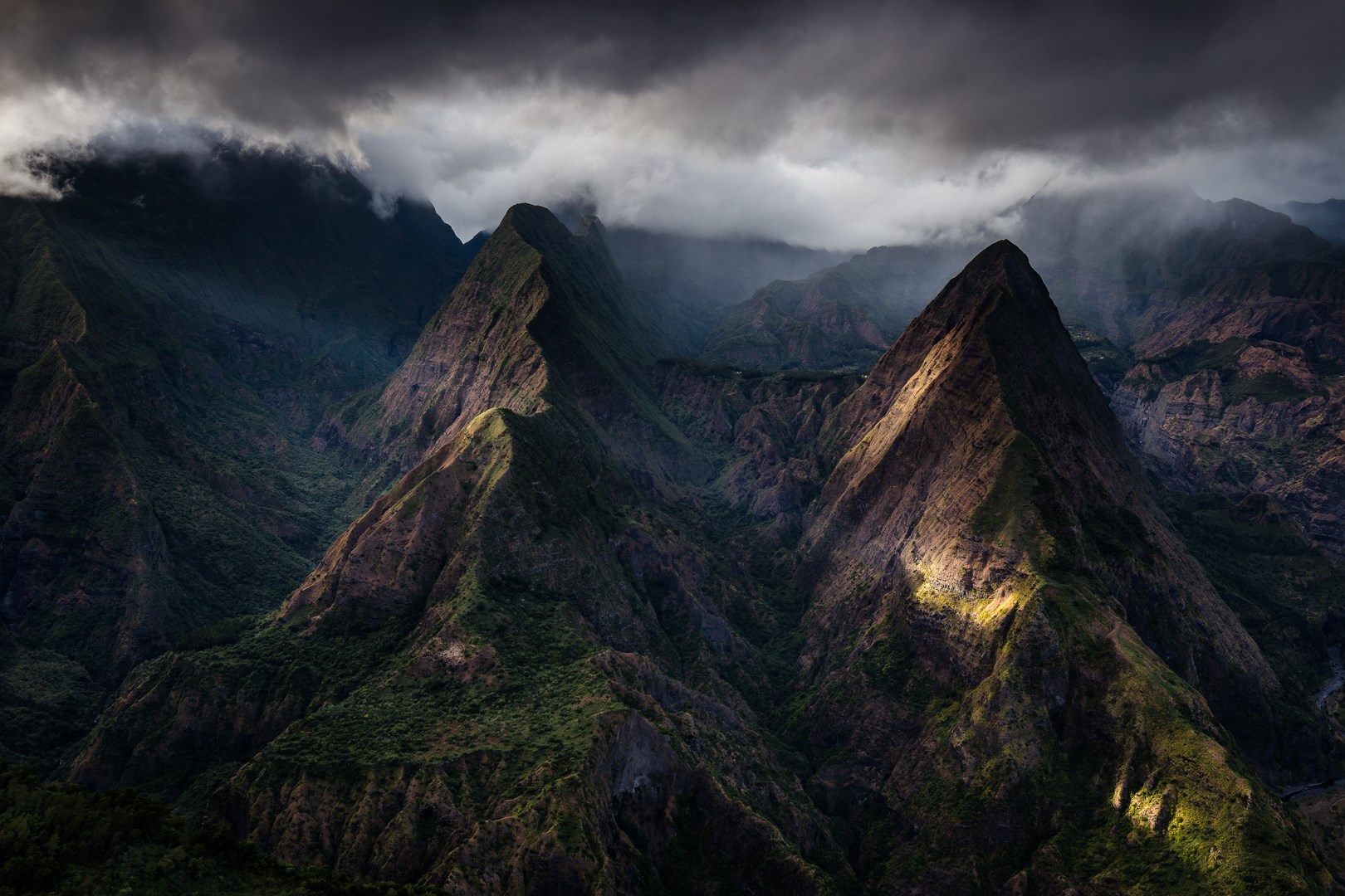 photo d'un paysage de montagne verdoyantes avec un ciel de nuage gris et un faisceaux de lumière
